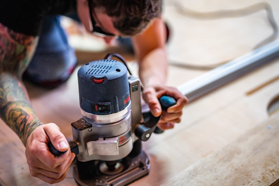 Hands using a router on a workbench